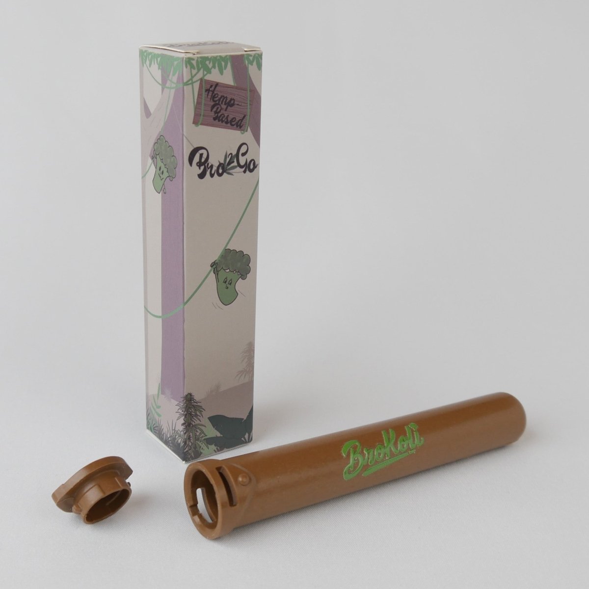 Der Hemp-Based Bro2Go von BroKoli, ein braunes, kindersicheres Transport-Case für Joints aus pflanzenbasiertem Hanf-Kunststoff-Biokomposit. Neben dem geöffneten Case steht die Verpackung mit Dschungel-Design, das Kletterpflanzen und ein BroKoli Maskottchen zeigt.