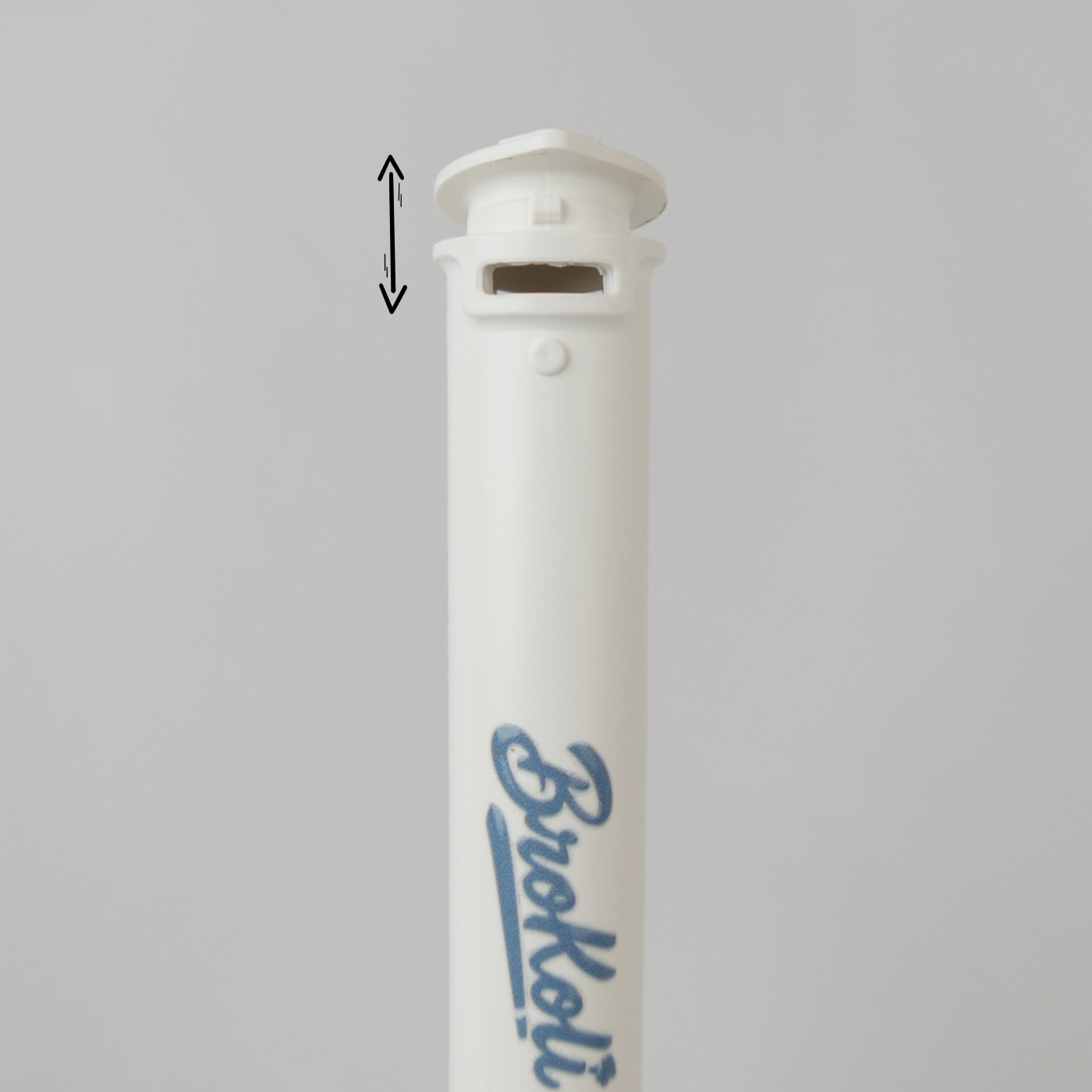 Nahaufnahme des Ocean-Bound Bro2Go von BroKoli, einem weißen Transport-Case mit kindersicherem Verschlussmechanismus. Der Deckel ist leicht angehoben, und eine schwarze Pfeilgrafik zeigt die Öffnungsbewegung an. Das BroKoli-Logo ist in Blau auf dem Tube aufgedruckt.