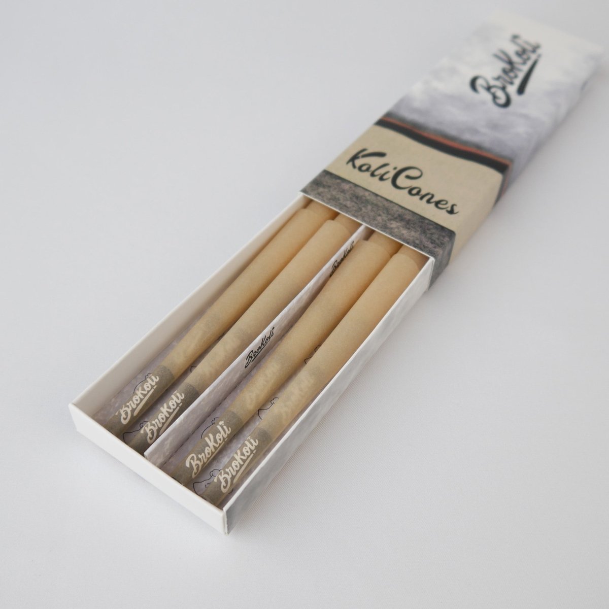 12er Pack Natural Brown Colored Tip KoliCones von BroKoli in einer stilvollen Verpackung. Die warmbraunen Cones sind teilweise aus der Box herausgezogen und zeigen das BroKoli-Logo auf den Black Tips.