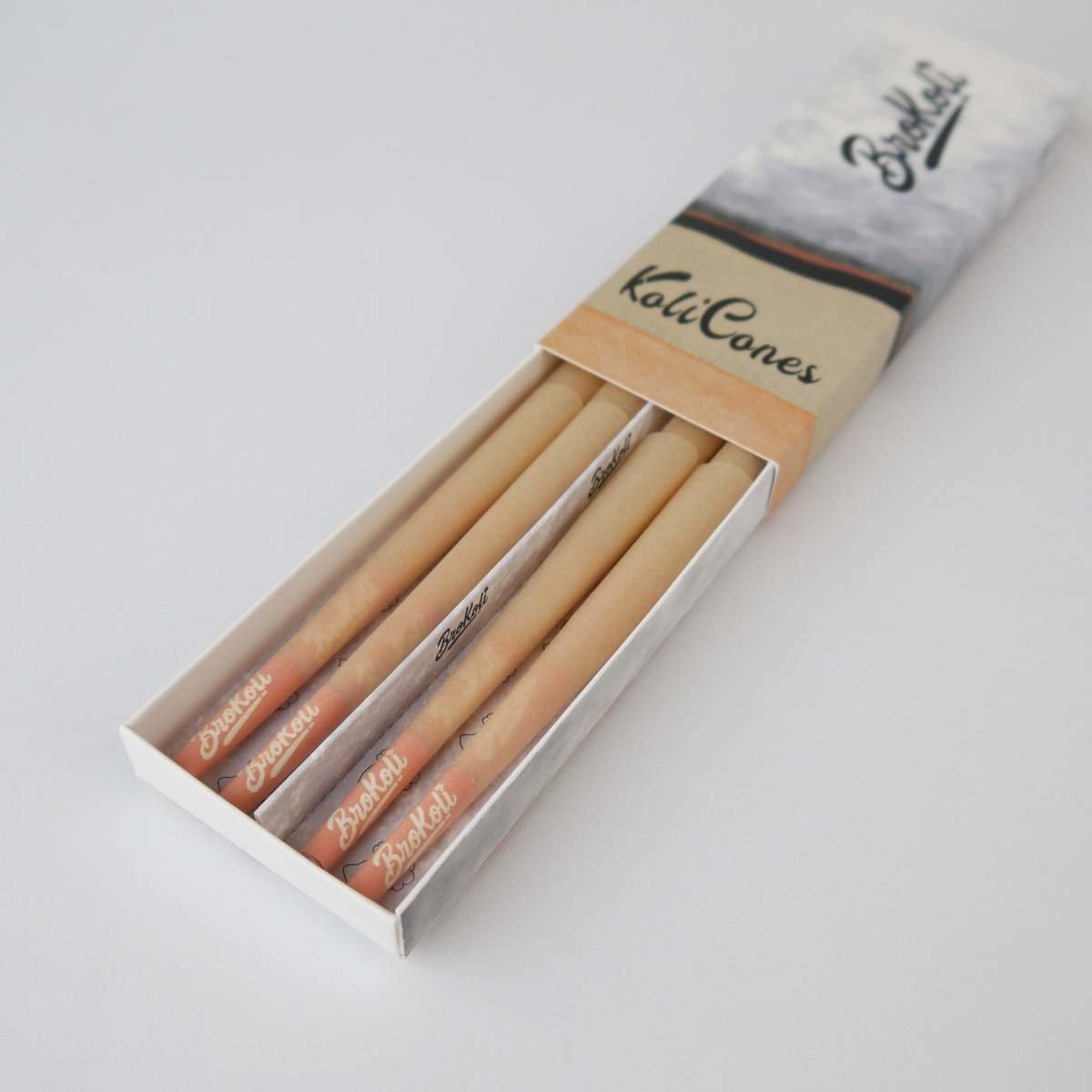 12er Pack Natural Brown Colored Tip KoliCones von BroKoli in einer stilvollen Verpackung. Die warmbraunen Cones sind teilweise aus der Box herausgezogen und zeigen das BroKoli-Logo auf den Orange Tips.