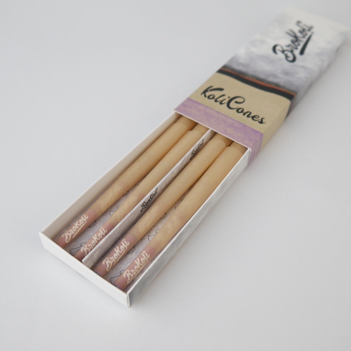 12er Pack Natural Brown Colored Tip KoliCones von BroKoli in einer stilvollen Verpackung. Die warmbraunen Cones sind teilweise aus der Box herausgezogen und zeigen das BroKoli-Logo auf den Purple Tips.