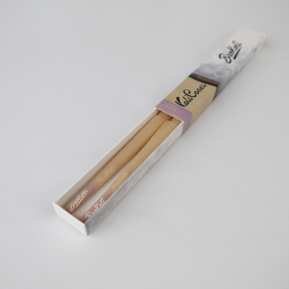 6er Pack Natural Brown Colored Tip KoliCones von BroKoli in einer stilvollen Verpackung. Die warmbraunen Cones sind teilweise aus der Box herausgezogen und zeigen das BroKoli-Logo auf den Purple Tips.