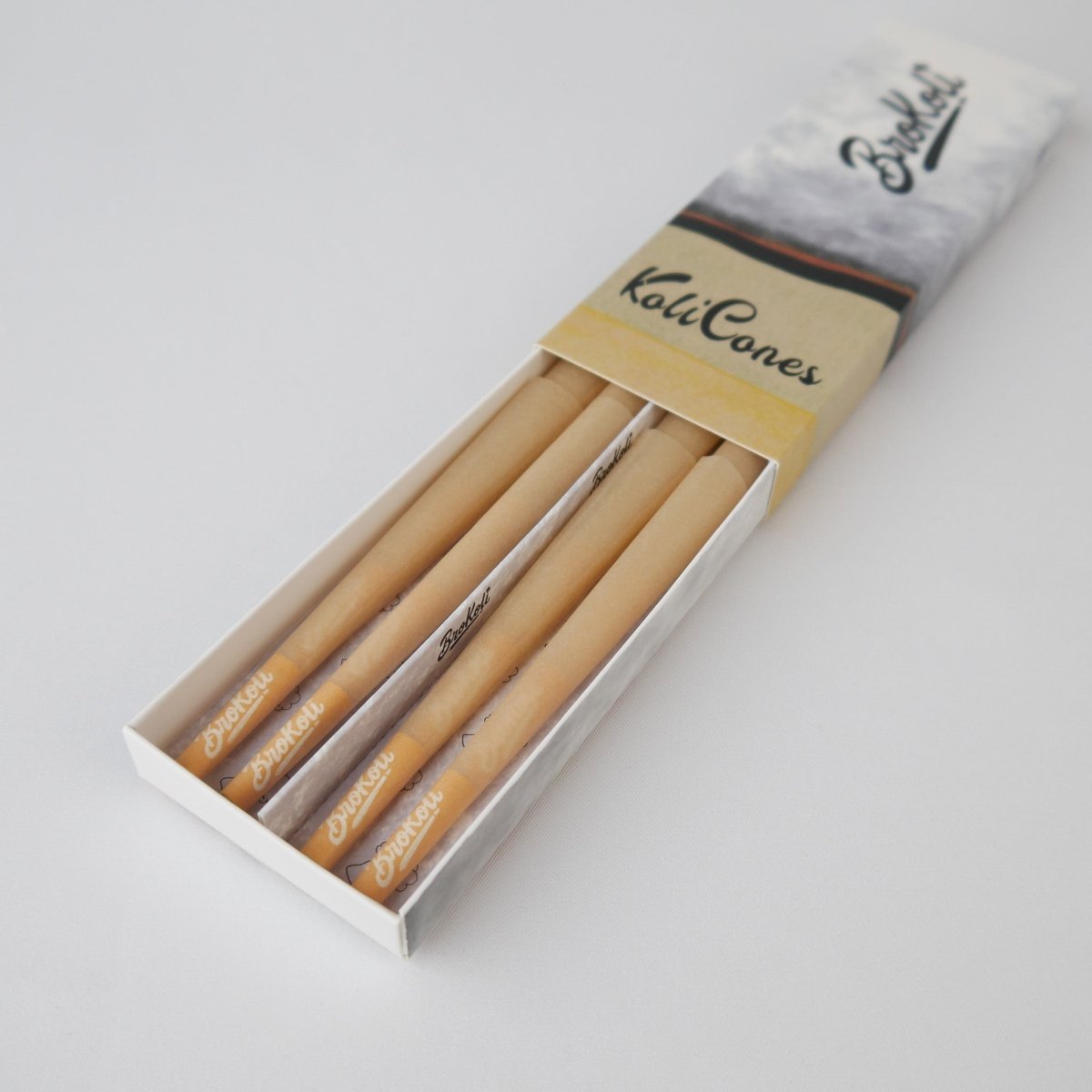 12er Pack Natural Brown Colored Tip KoliCones von BroKoli in einer stilvollen Verpackung. Die warmbraunen Cones sind teilweise aus der Box herausgezogen und zeigen das BroKoli-Logo auf den Yellow Tips.