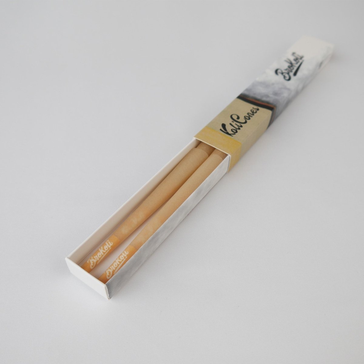 6er Pack Natural Brown Colored Tip KoliCones von BroKoli in einer stilvollen Verpackung. Die warmbraunen Cones sind teilweise aus der Box herausgezogen und zeigen das BroKoli-Logo auf den Yellow Tips.