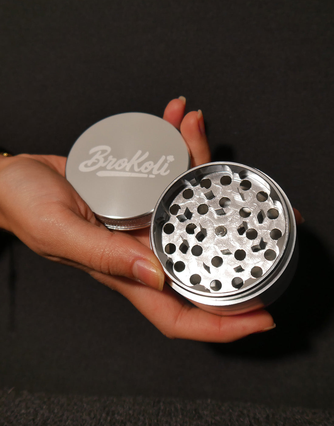 KoliGrinder – langlebiger Aluminium-Grinder mit scharfem Mahlwerk, in der Hand gehalten, mit BroKoli-Logo auf dem Deckel.