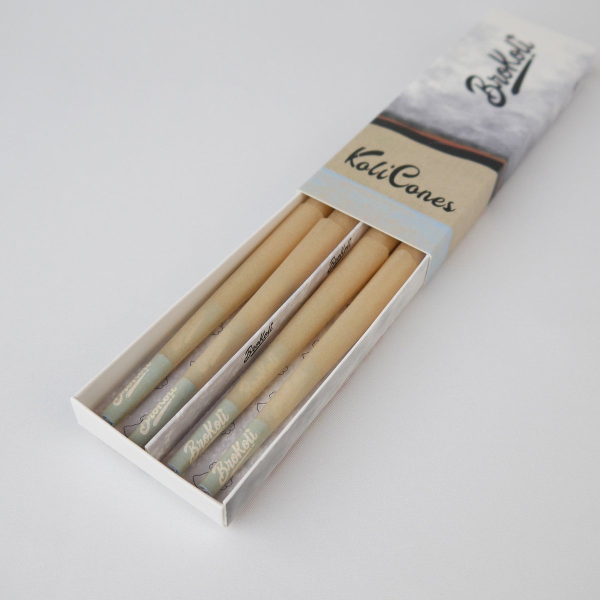 12er Pack Natural Brown Colored Tip KoliCones von BroKoli in einer stilvollen Verpackung. Die warmbraunen Cones sind teilweise aus der Box herausgezogen und zeigen das BroKoli-Logo auf den Blue Tips.