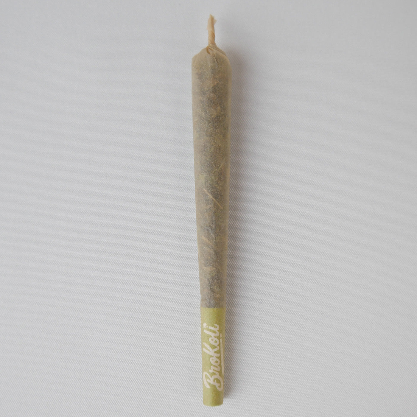 Ein gefüllter Colored Tip KoliCone liegt auf weißem Hintergrund. Der Cone hat einen Green Tip mit BroKoli-Logo und ein leicht transparentes Paper, durch das der Inhalt sichtbar ist. Das obere Ende ist eingedreht.