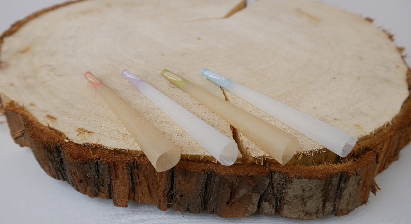 Vier BroKoli KoliCones auf einer Holzscheibe: Natural Brown Colored Tip KoliCone mit rotem Filter, Refined White Colored Tip KoliCone mit lila Filter, Natural Brown Colored Tip KoliCone mit grünem Filter und Refined White Colored Tip KoliCone mit blauem Filter.