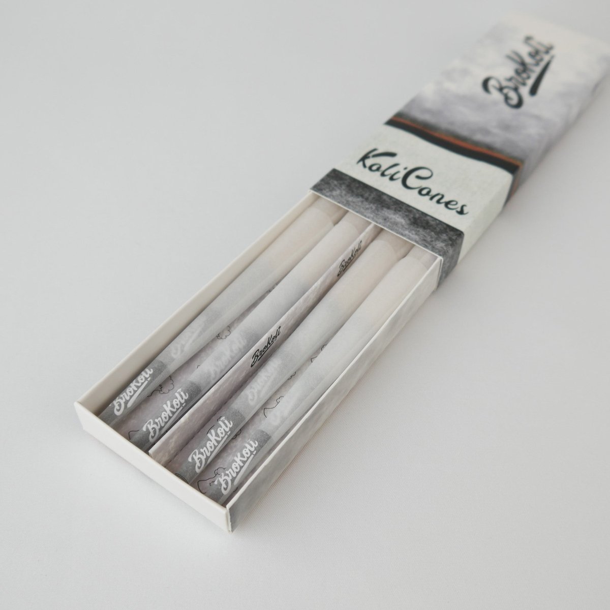 12er Pack Refined White Colored Tip KoliCones von BroKoli in einer stilvollen Verpackung. Die hellen, veredelten Cones sind teilweise aus der Box herausgezogen und zeigen das BroKoli-Logo auf den Black Tips.