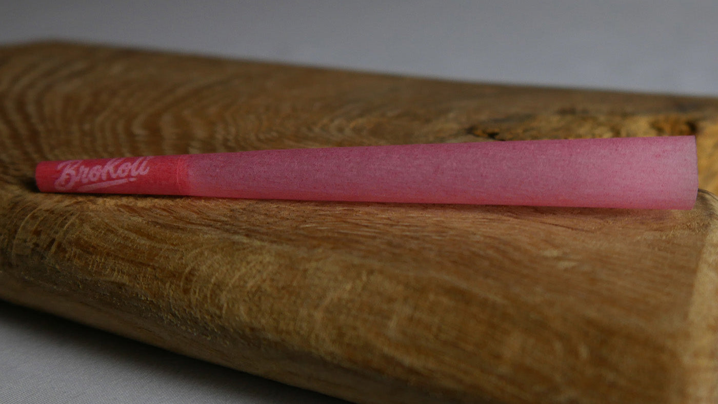 Ein einzelner Red Pastel Cone von BroKoli auf einer rustikalen Holzunterlage. Der Cone leuchtet in sanftem Rot. Der farblich passende Tip trägt das BroKoli-Logo und rundet das stilvolle Design ab.